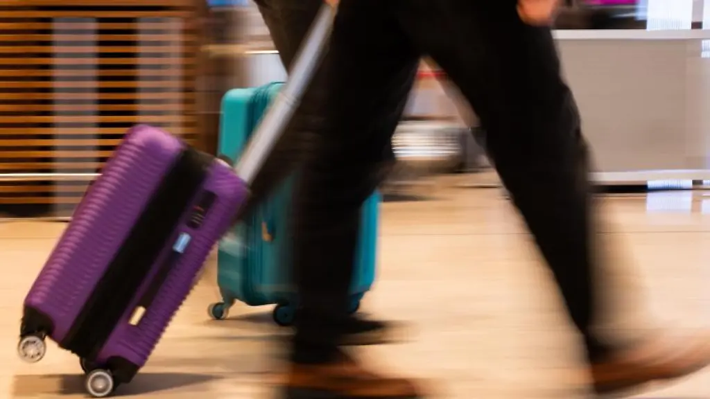 Menschen-gehen-am-Flughafen-Berlin-Brandenburg-mit-Gepaeck-durch-die-Haupthalle