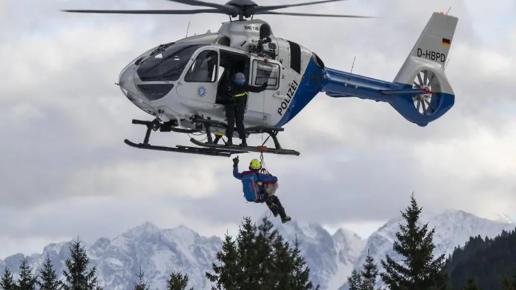 Ein-Hundefuehrer-der-Bergrettung-haengt-mit-Hilfe-eines-Seils-an-einem-Hubschrauber