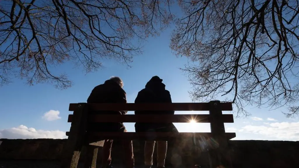 Ein-Mann-und-eine-Frau-sitzen-in-der-Sonne-auf-einer-Bank