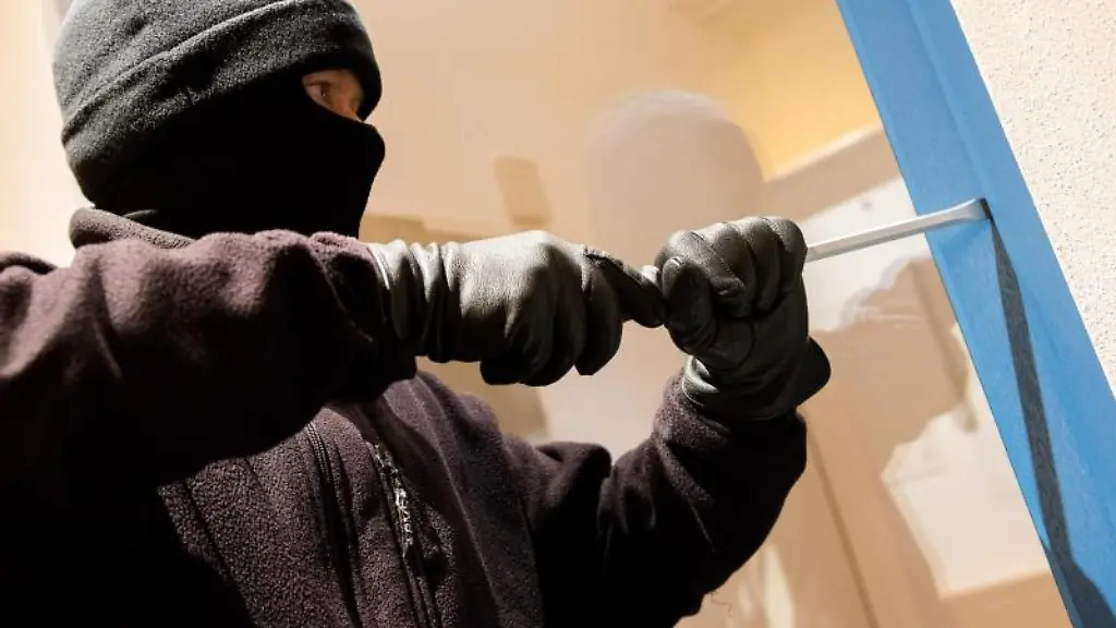 Ein-als-Einbrecher-verkleideter-Mann-hebelt-ein-Fenster-auf