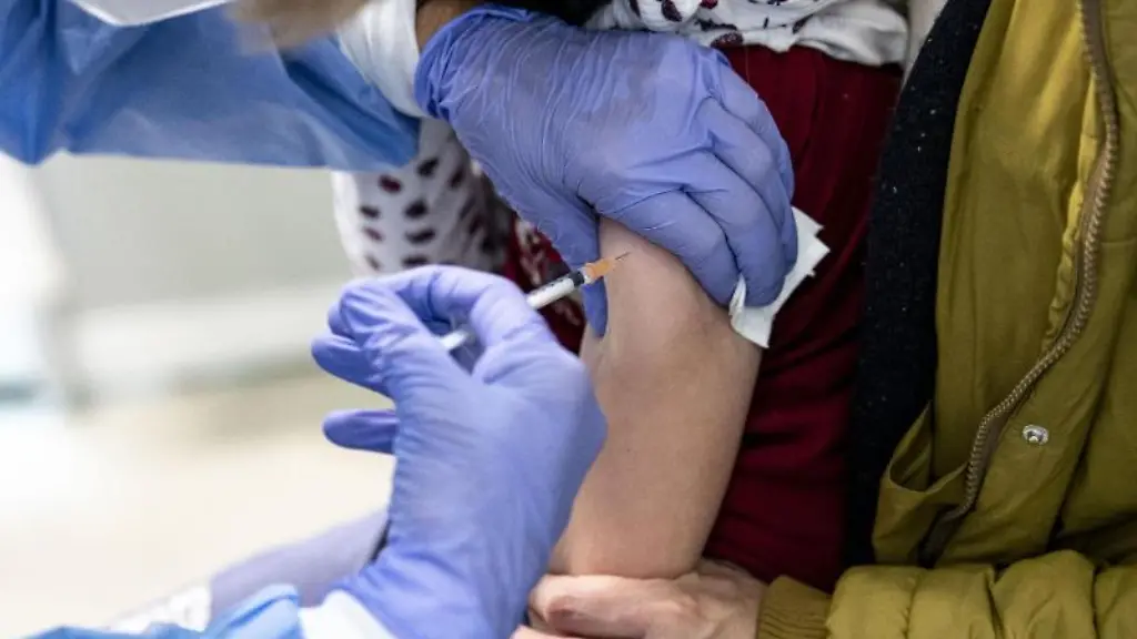 Eine-Aerztin-impft-ein-6-jaehriges-Maedchen-das-auf-dem-Schoss-der-Mutter-sitzt