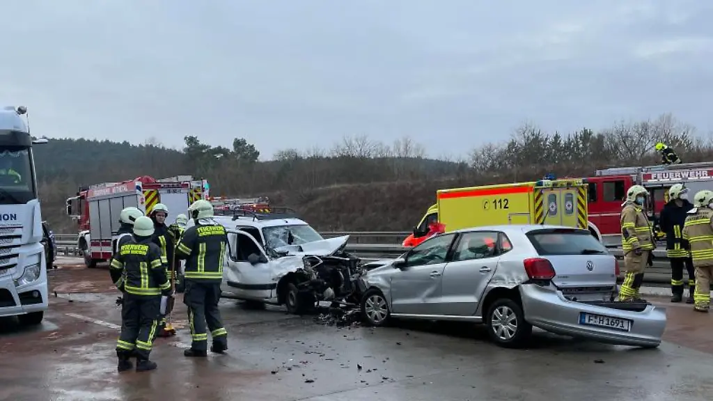 Feuerwehrmaenner-stehen-neben-beschaedigten-Autos-die-in-einen-Unfall-verwickelt-waren