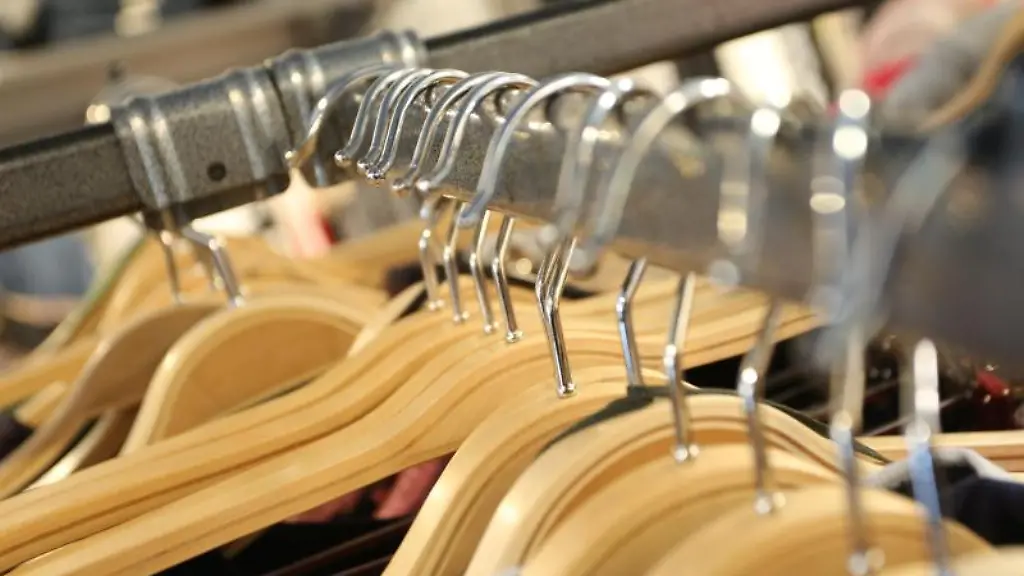 Kleiderbuegel-mit-Modeartikeln-haengen-an-einem-Verkaufsstaender-in-einem-Modegeschaeft