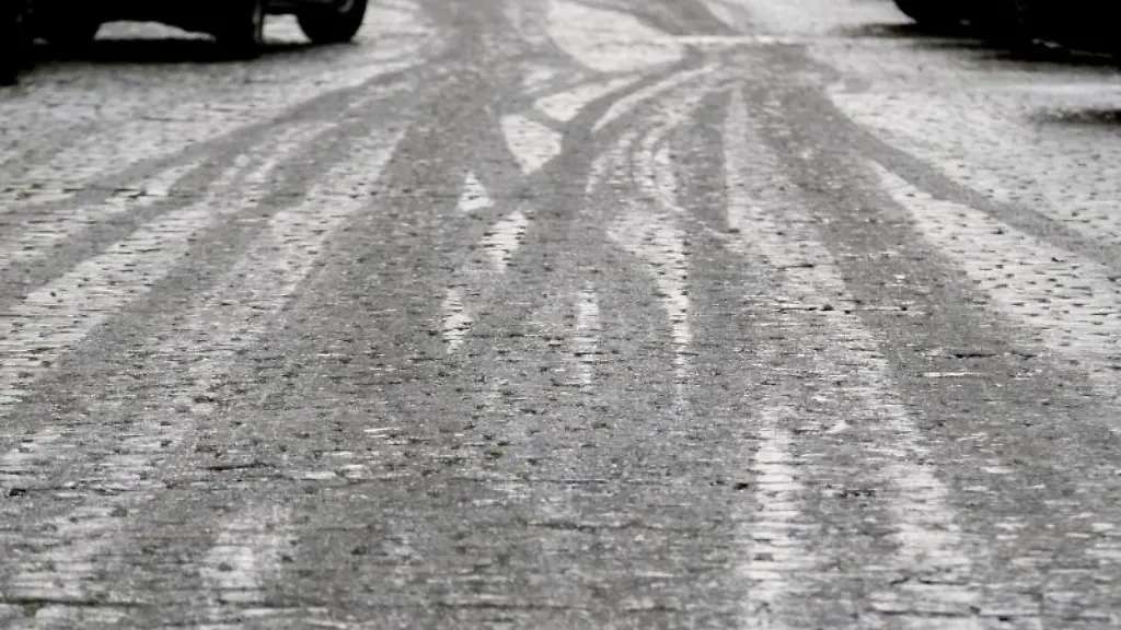 Fahrspuren-zeichnen-sich-im-Eis-auf-einer-Fahrbahn-ab