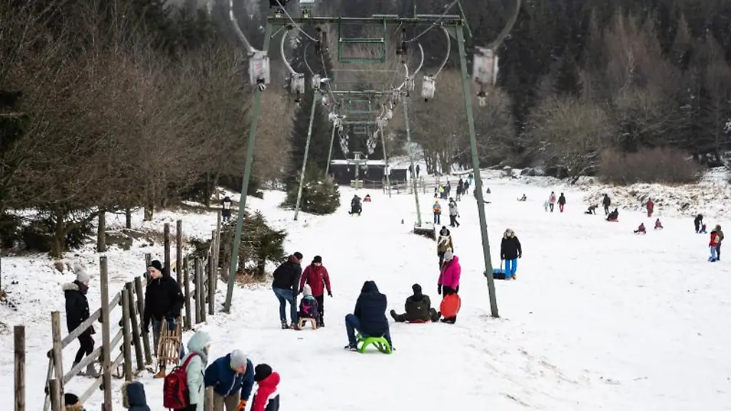 Wintersportler-sind-mit-Schlitten-an-einem-Hang-unterwegs
