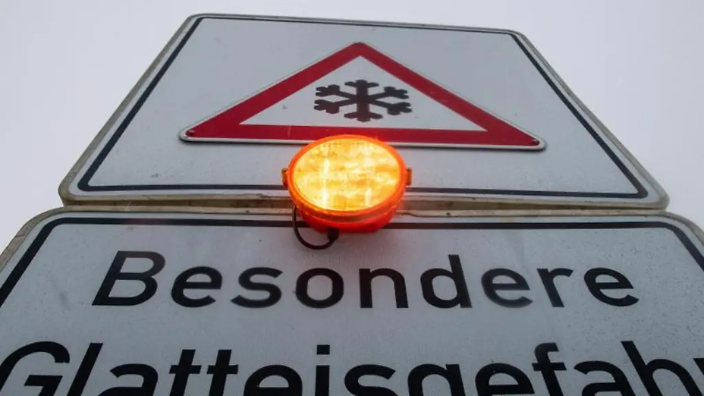 Ein-Strassenschild-warnt-mit-einer-Blinkleuchte-vor-Glatteis