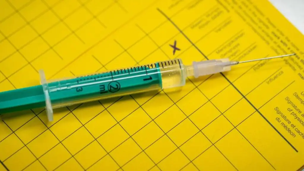 Eine-Spritze-liegt-auf-einem-Impfpass