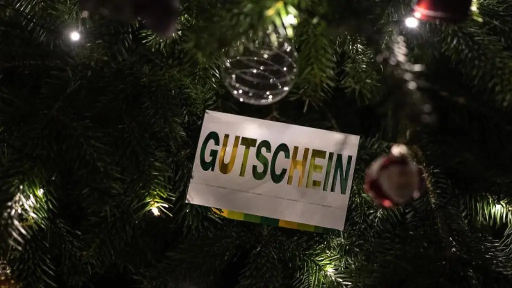 Ein-Umschlag-mit-der-Aufschrift-Gutschein-ist-an-einem-geschmueckten-Weihnachtsbaum-zu-sehen