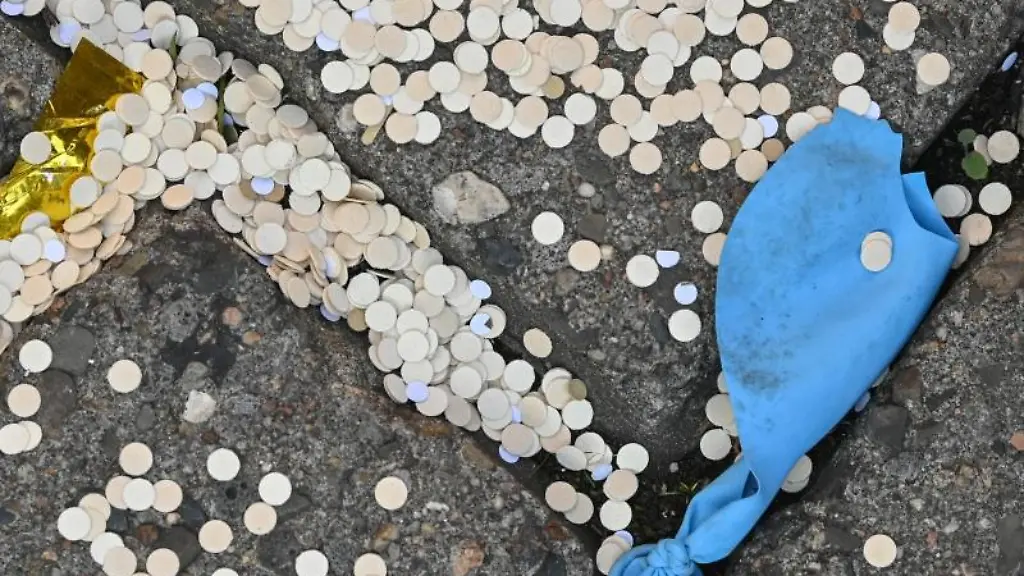 Konfetti-und-ein-kaputter-Luftballon-liegen-auf-einem-Gehweg