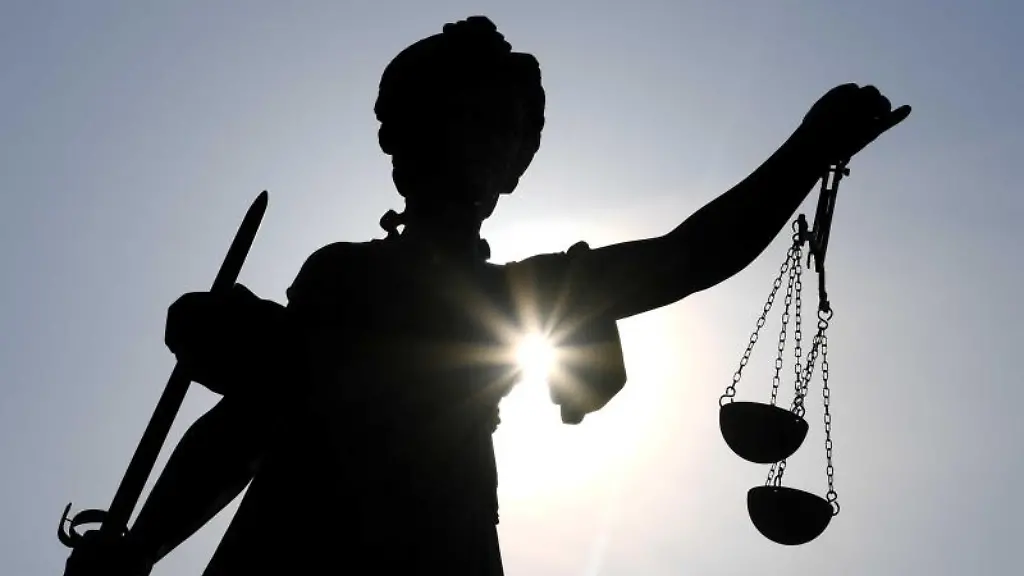 Eine-Statue-der-Justitia-steht-mit-Waage-und-Schwert-in-der-Hand