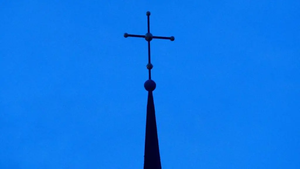 Das-Kreuz-einer-Kirche-ist-in-der-Abenddaemmerung-zu-sehen