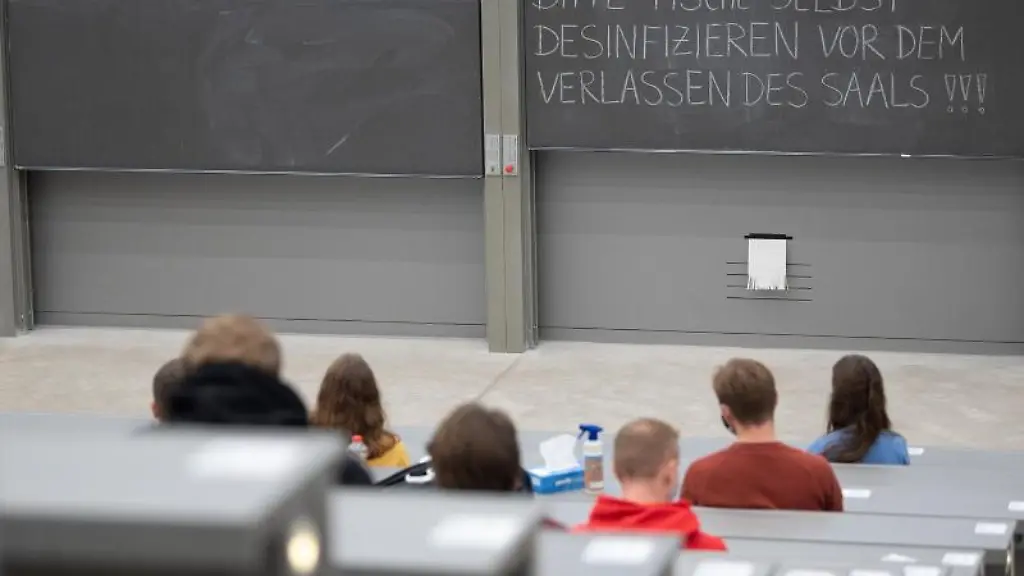 Studierende-mit-Mund-und-Nasenmaske-sitzen-in-einem-Hoersaal