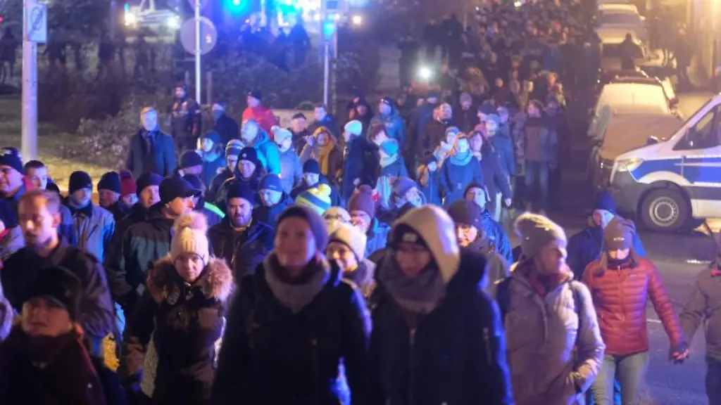 Kritiker-der-Coronamassnahmen-gehen-eine-Strasse-entlang