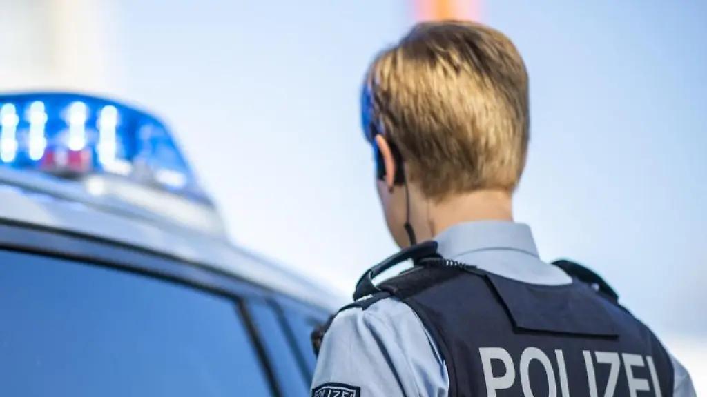 Eine-Polizistin-steht-vor-einem-Streifenwagen