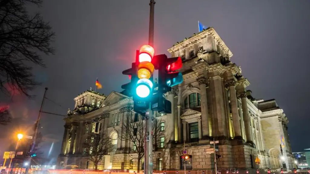 Eine-Ampel-leuchtet-am-Morgen-vor-dem-Reichstagsgebaeude-in-allen-drei-Phasen