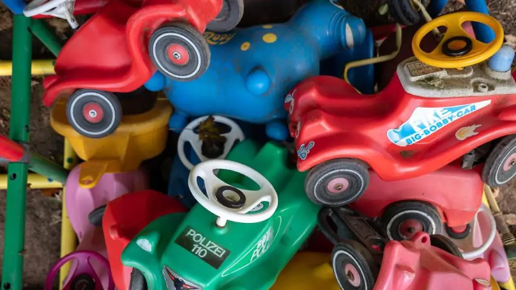 Bobbycars-liegen-in-einer-Kita-in-einer-Einzaeunung