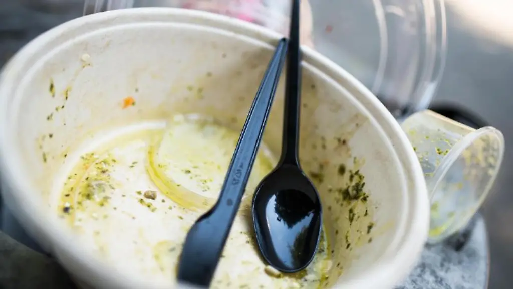 Gebrauchtes-Plastikgeschirr-liegt-auf-einem-Muelleimer