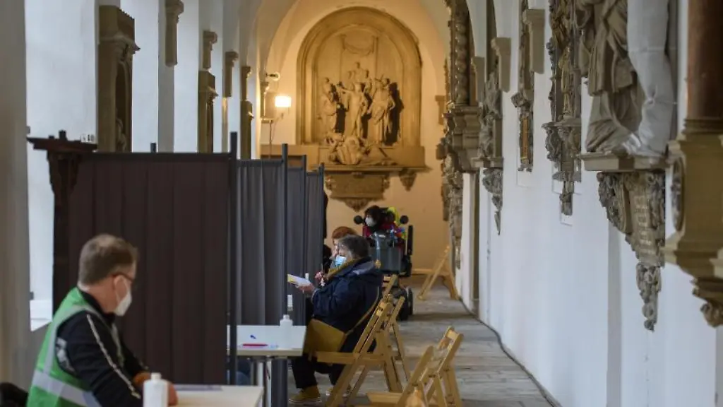 Menschen-sitzen-im-Kreuzgang-des-Doms-und-erhalten-eine-Beratung-zur-Corona-Impfung