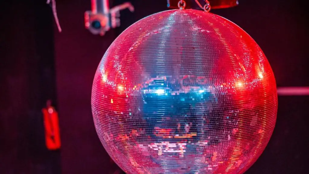 Eine-farbig-beleuchtete-Discokugel-dreht-sich-ueber-einer-Tanzflaeche