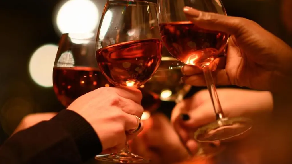 Gaeste-stossen-in-einem-Restaurant-mit-ihren-Weinglaesern-an