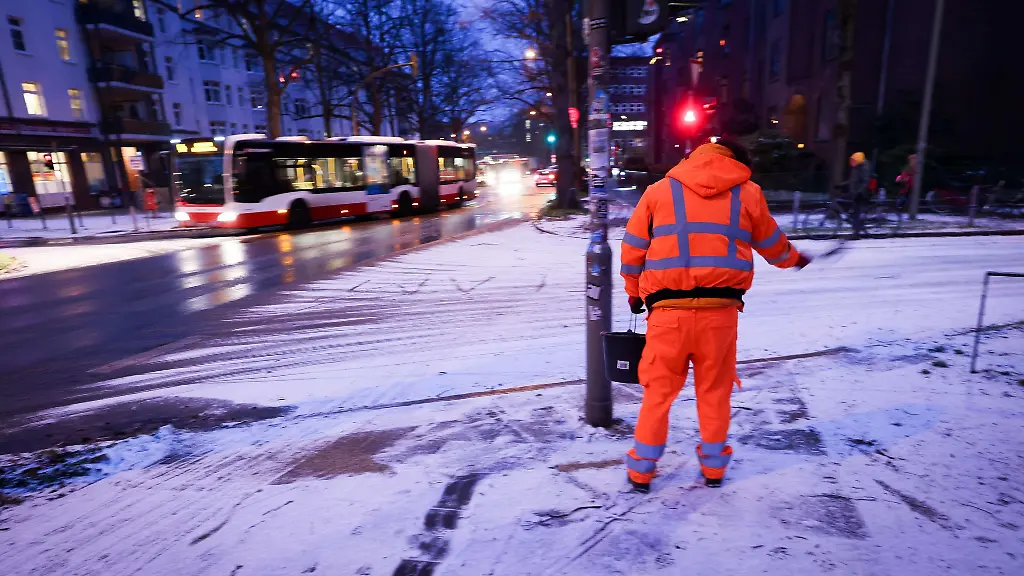 Ein-Mitarbeiter-der-Stadtreinigung-streut-nach-leichtem-Schneefall-Salz