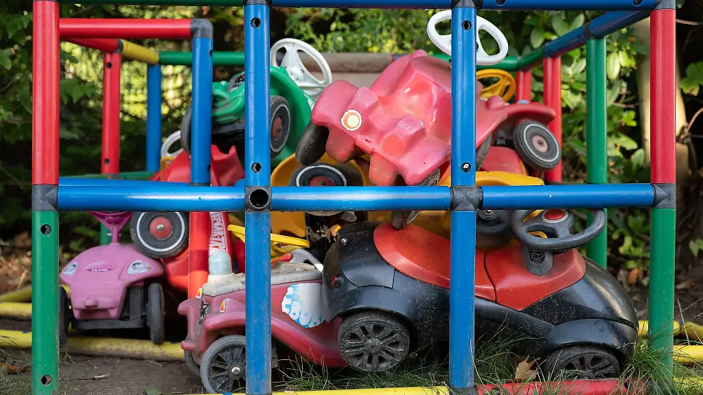 Bobbycars-liegen-in-einer-Kita-in-einer-Einzaeunung