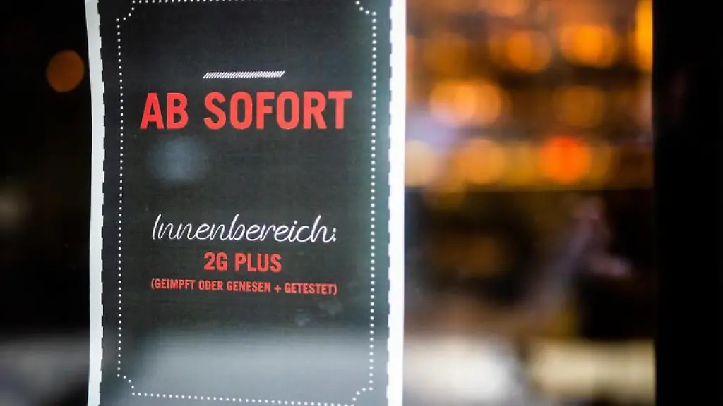 Ein-Plakat-weist-Gaeste-am-Eingang-eines-Restaurants-auf-die-neue-2G-Plus-Regel-hin