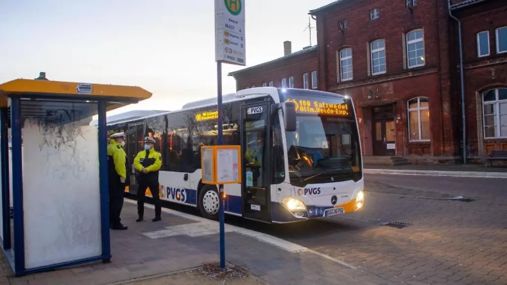 Polizisten-stehen-an-einer-Bushaltestelle-waehrend-ein-Bus-abfaehrt