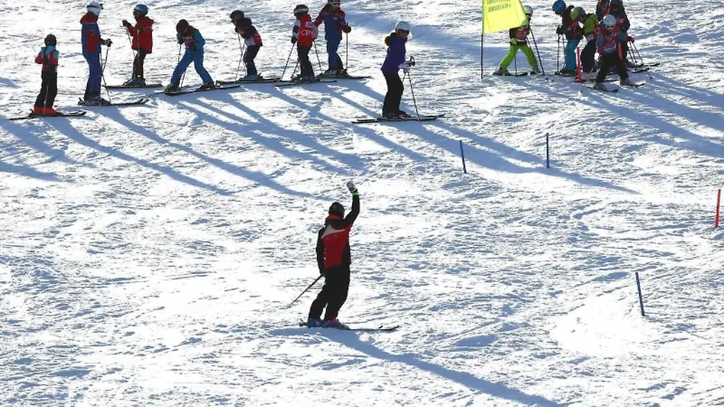 Junge-Teilnehmer-eines-Ski-Kurses-fahren-in-der-Ski-Arena-im-Thueringer-Wald-einen-Hang-hinab