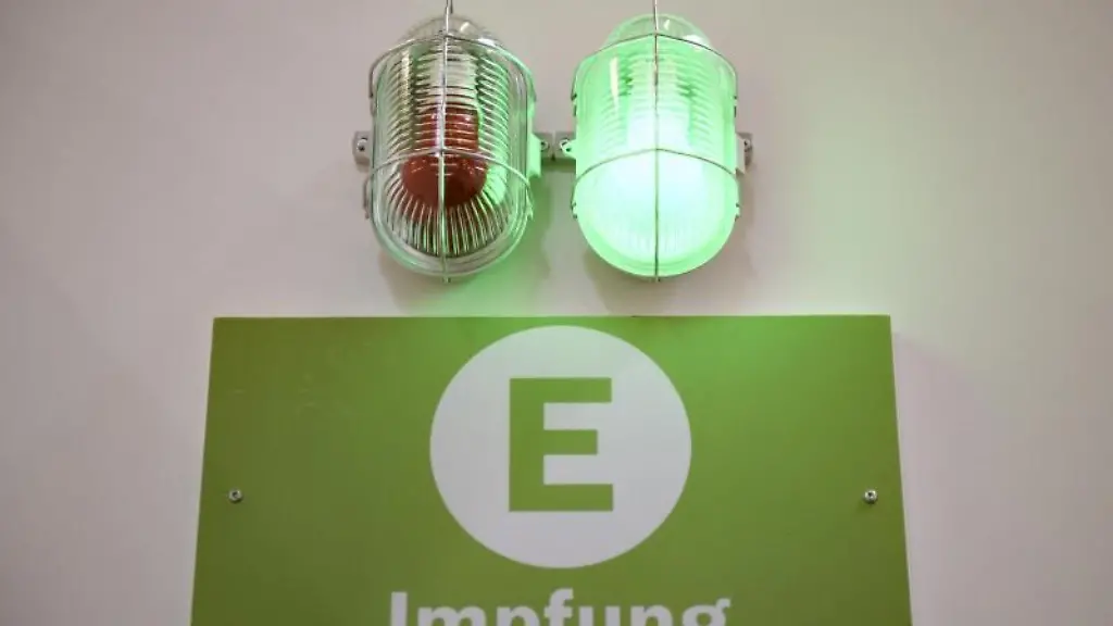 Eine-gruene-Lampe-leuchtet-ueber-einem-Schild-mit-der-Aufschrift-Impfung