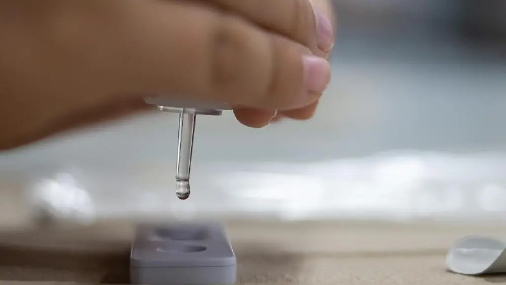 Eine-Person-tropft-eine-Fluessigkeit-in-einen-Corona-Schnelltest