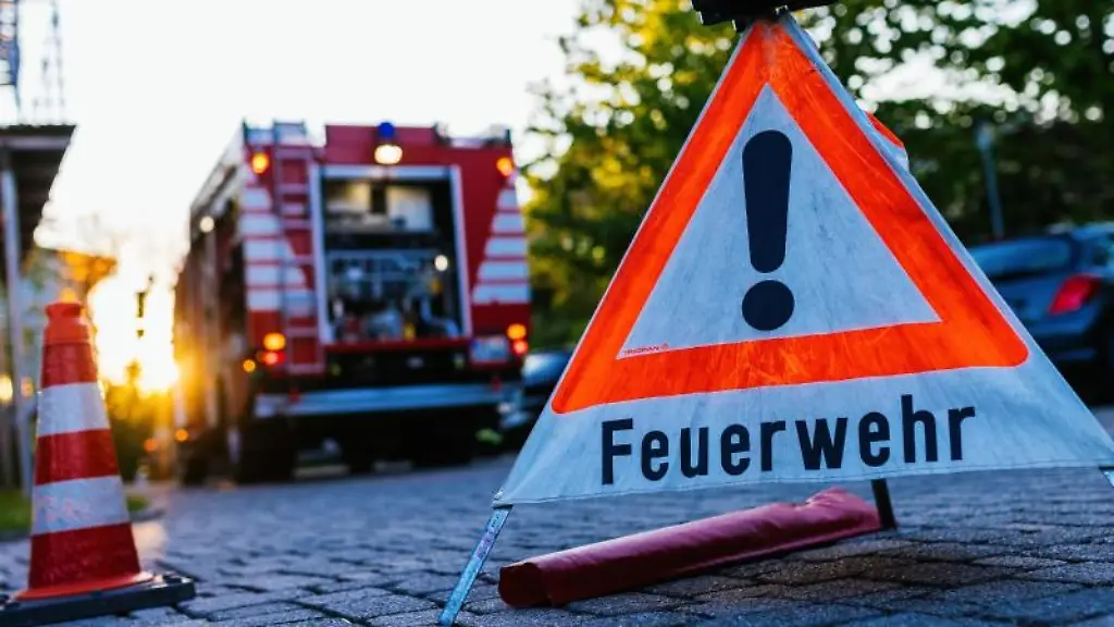 Ein-Warndreieick-mit-der-Aufschrift-Feuerwehr-steht-auf-dem-Hof-eines-Feuerwehrgeraetehauses