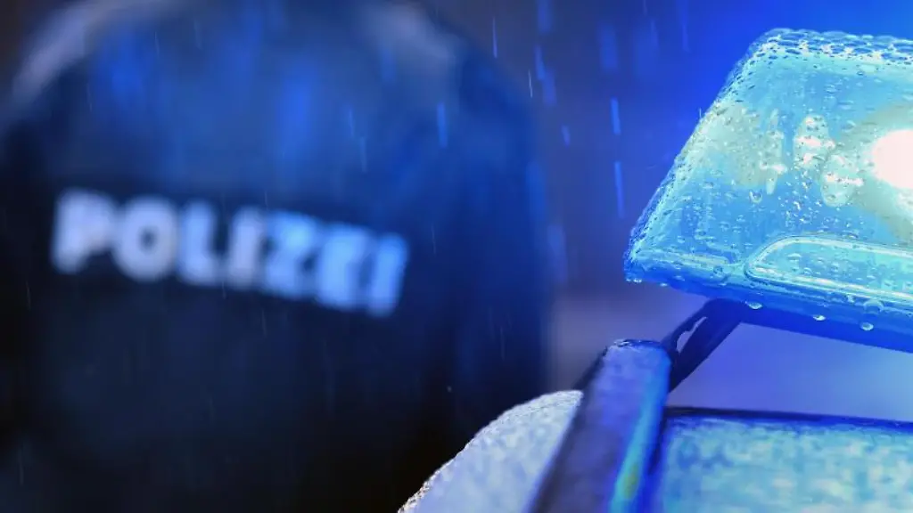 Ein-Polizist-steht-vor-einem-Streifenwagen-mit-Blaulicht