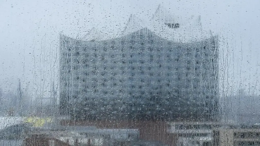 Regentropfen-fallen-auf-eine-Fensterscheibe-durch-die-die-Elbphilharmonie-zu-sehen-ist