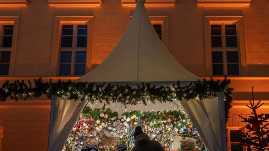 Besucher-eines-Weihnachtsmarktes-stehen-an-einem-Verkaufsstand-fuer-Christbaumschmuck