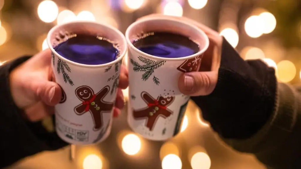 Zwei-Besucherinnen-eines-Weihnachtsmarktes-stossen-mit-Gluehwein-an