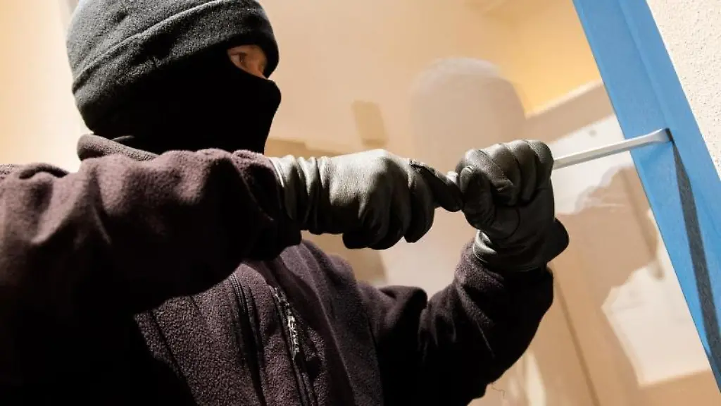 Ein-als-Einbrecher-verkleideter-Mann-hebelt-ein-Fenster-auf