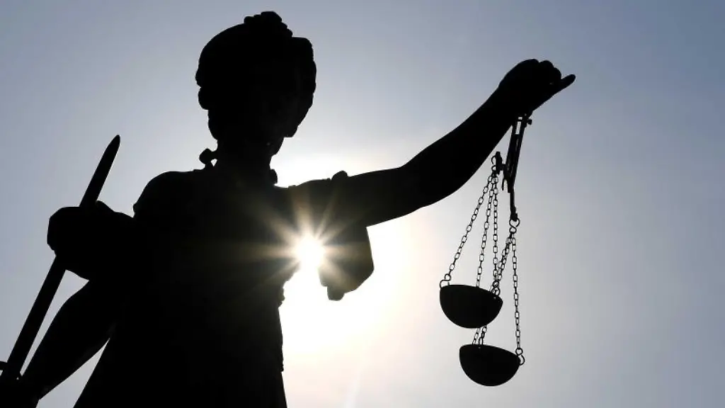 Eine-Statue-der-Justitia-steht-mit-Waage-und-Schwert-in-der-Hand