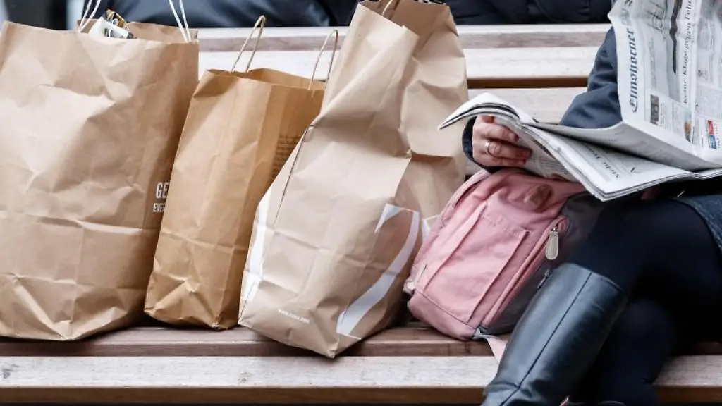Eine-Frau-sitzt-mit-ihren-Einkaufstaschen-auf-einer-Bank