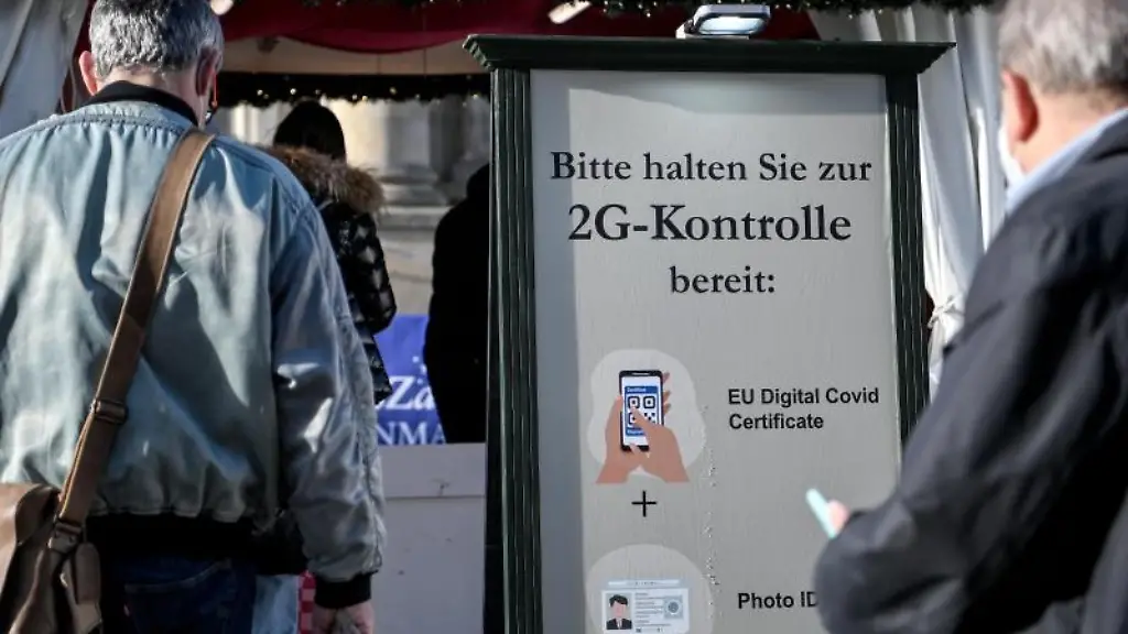 Besucher-stehen-bei-der-2G-Kontrolle-am-Eingang-vor-einem-Weihnachtsmarkt-an