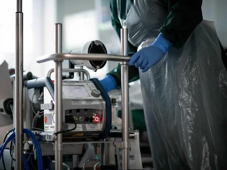 Eine-Pflegekraft-steht-auf-einer-Intensivstation-in-einem-Zimmer-und-bedient-eine-Herz-Lungen-Maschine