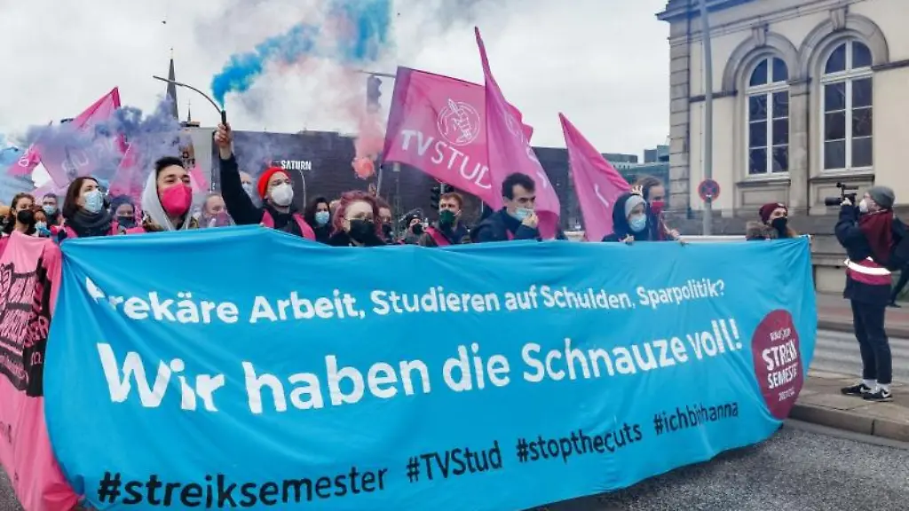 Streikende-ziehen-waehrend-eines-Warnstreiks-in-der-Tarifrunde-hinter-einem-Transparent