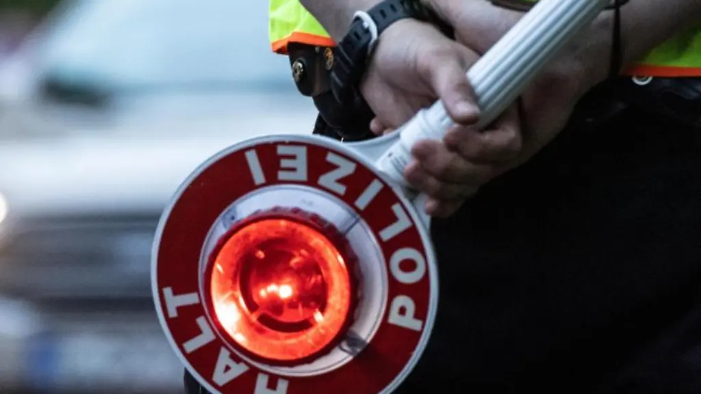 Ein-Polizist-haelt-bei-einer-Verkehrskontrolle-eine-Winkerkelle-in-der-Hand