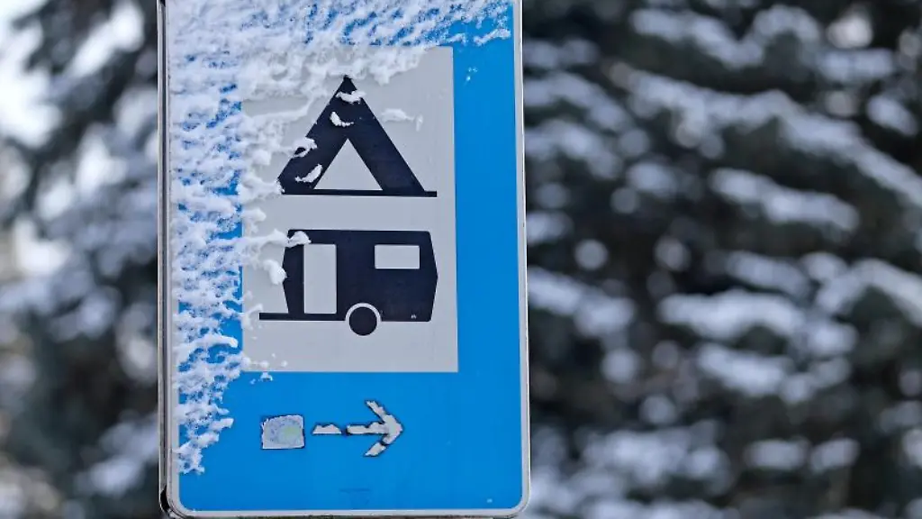 Ein-verschneites-Verkehrsschild-weist-den-Weg-zu-einem-Campingplatz