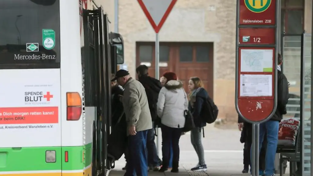 Fahrgaeste-steigen-an-einem-Busbahnhof-in-einen-Bus