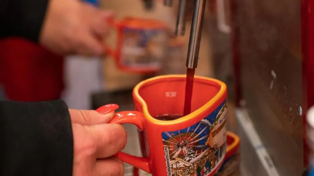 Eine-Frau-fuellt-auf-dem-Weihnachtsrummel-Winterzauber-Berlin-eine-Tasse-mit-Gluehwein