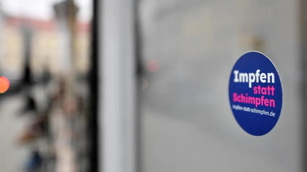 Impfen-statt-Schimpfen-steht-auf-einem-Aufkleber-an-der-Fensterscheibe-eines-Geschaefts-in-Weimar