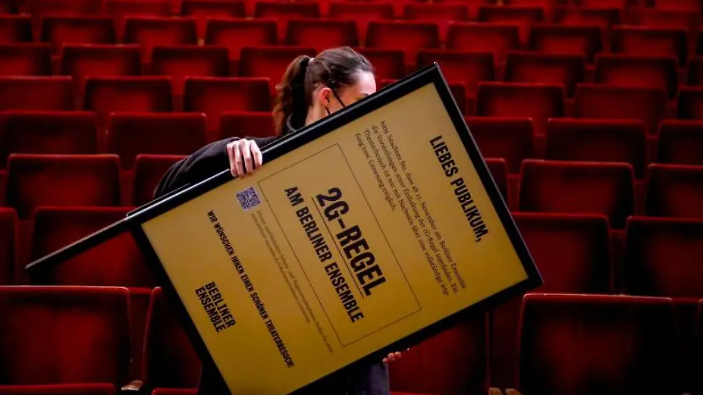 Eine-Mitarbeiterin-traegt-einen-Aufsteller-mit-dem-Hinweis-auf-die-2G-Regel