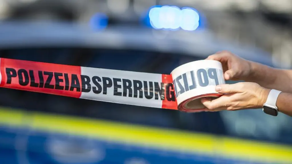 Eine-Frau-rollt-ein-Absperrband-der-Polizei-aus