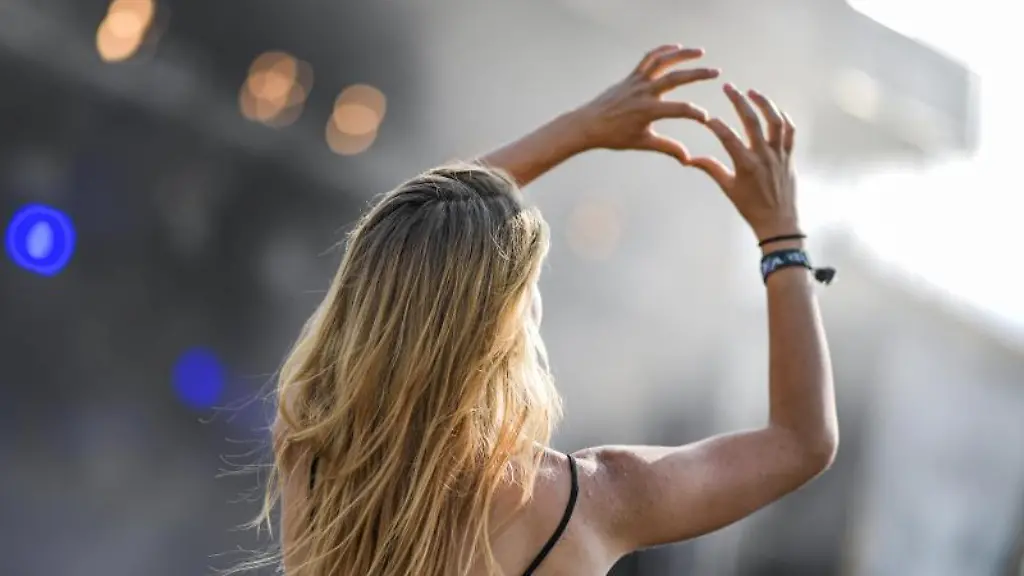 Eine-Frau-formt-bei-einem-Konzert-vor-einer-Buehne-die-Haende-zu-einem-Herz